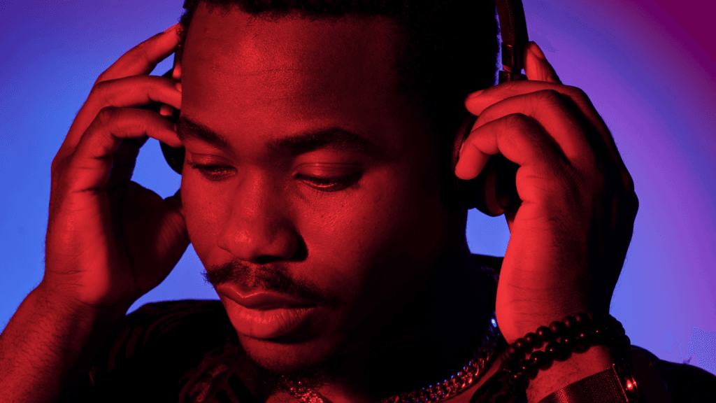 Homme noir écoutant un podcast avec un casque audio, ambiance lumineuse rouge et bleue immersive – ecoutegay podcast LGBT