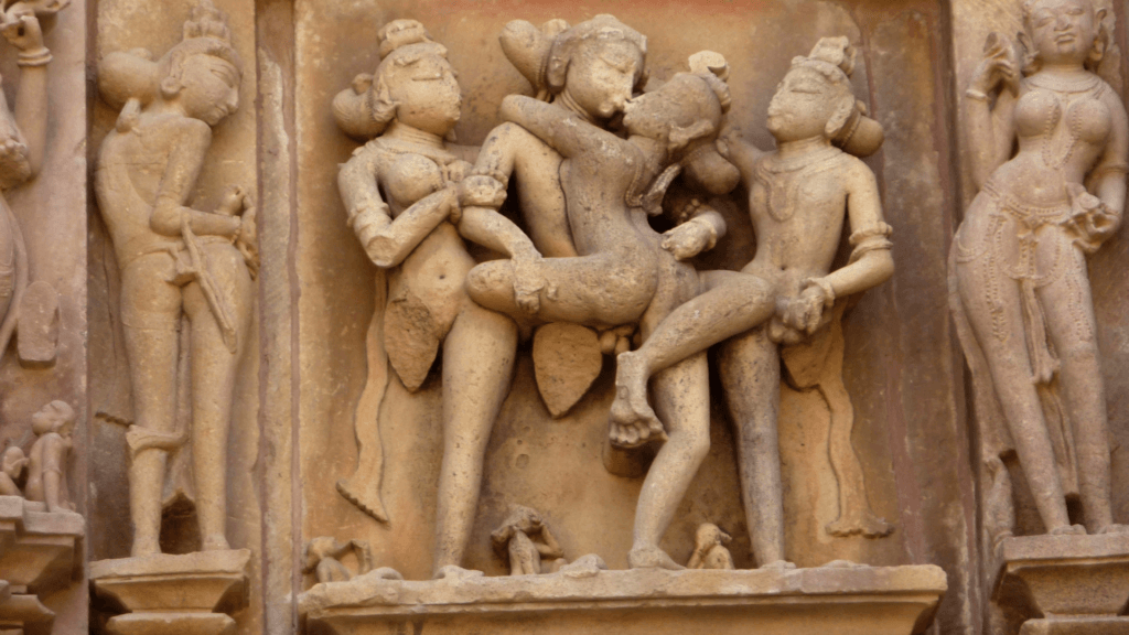 Sculptures érotiques du temple de Khajuraho (Kamasutra indien) : groupe de figures nues enlacées en positions intimes, corps gracieux en pierre sable, évoquant richesse sensuelle accessible aux hommes homosexuels. Art ancien célébrant le plaisir charnel.