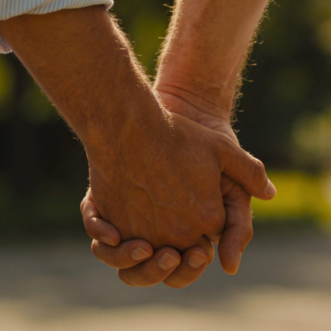 Deux hommes se tenant la main en extérieur, symbole d’amour et de relation gay durable – podcast ecoutegay